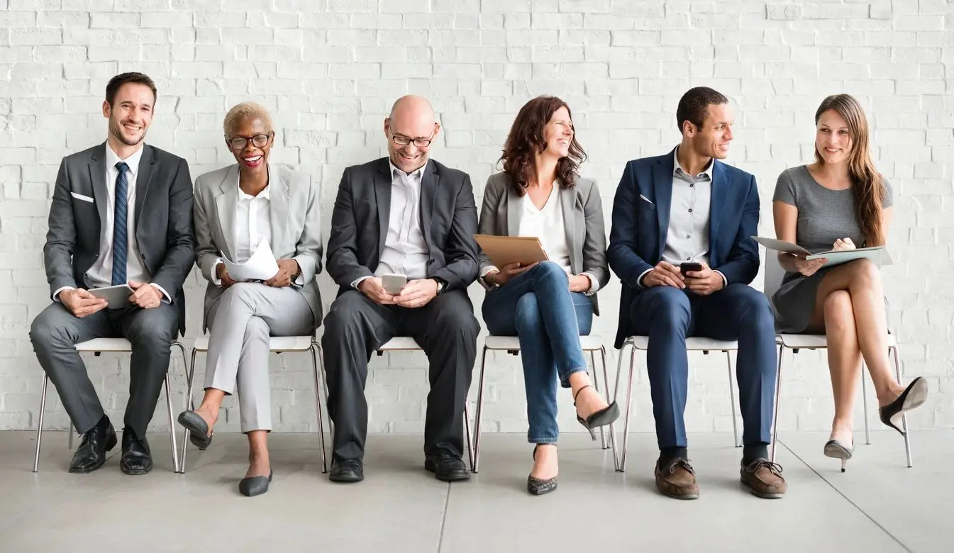 A group of people sitting on chairs in front of a wall.